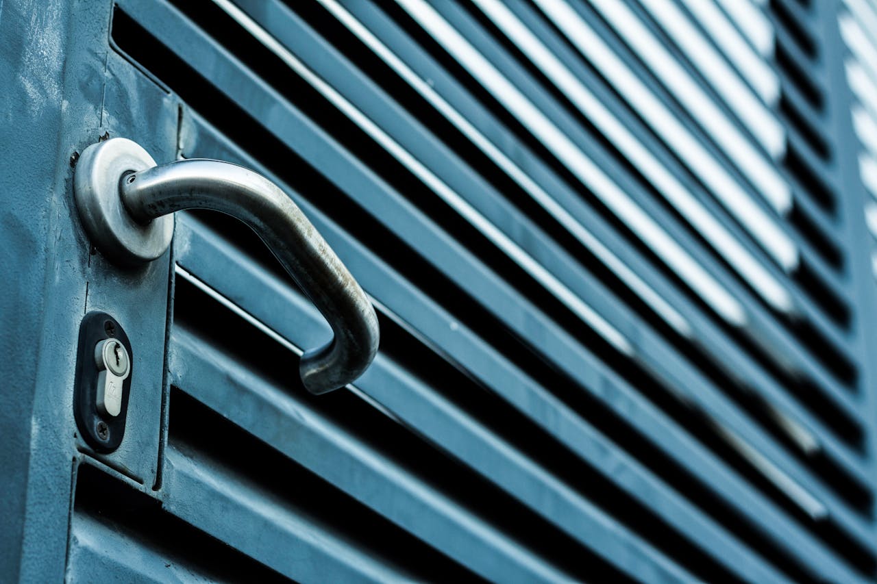 About Close-up of a sleek stainless steel door handle and lock on a blue metallic door.