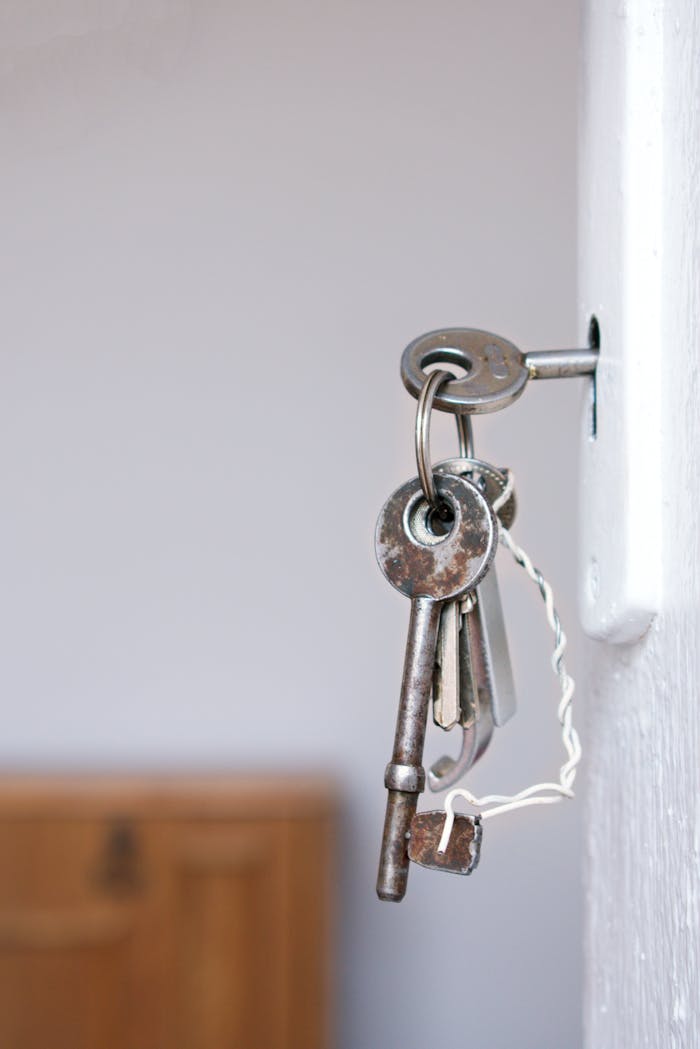 Home Close-up of vintage keys in a door keyhole with rustic metal and wood textures.